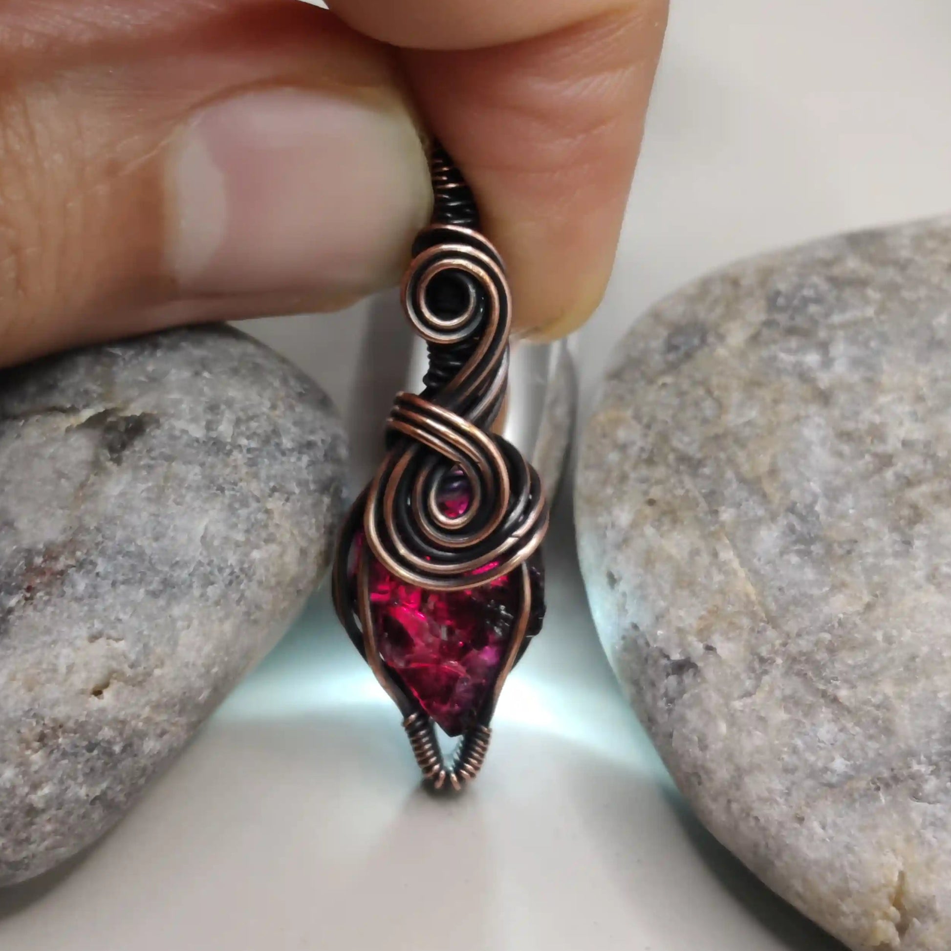 Niyati raw garnet pendant in antiqued copper 001 with light source in the background made by sanguine aura healing jewellery