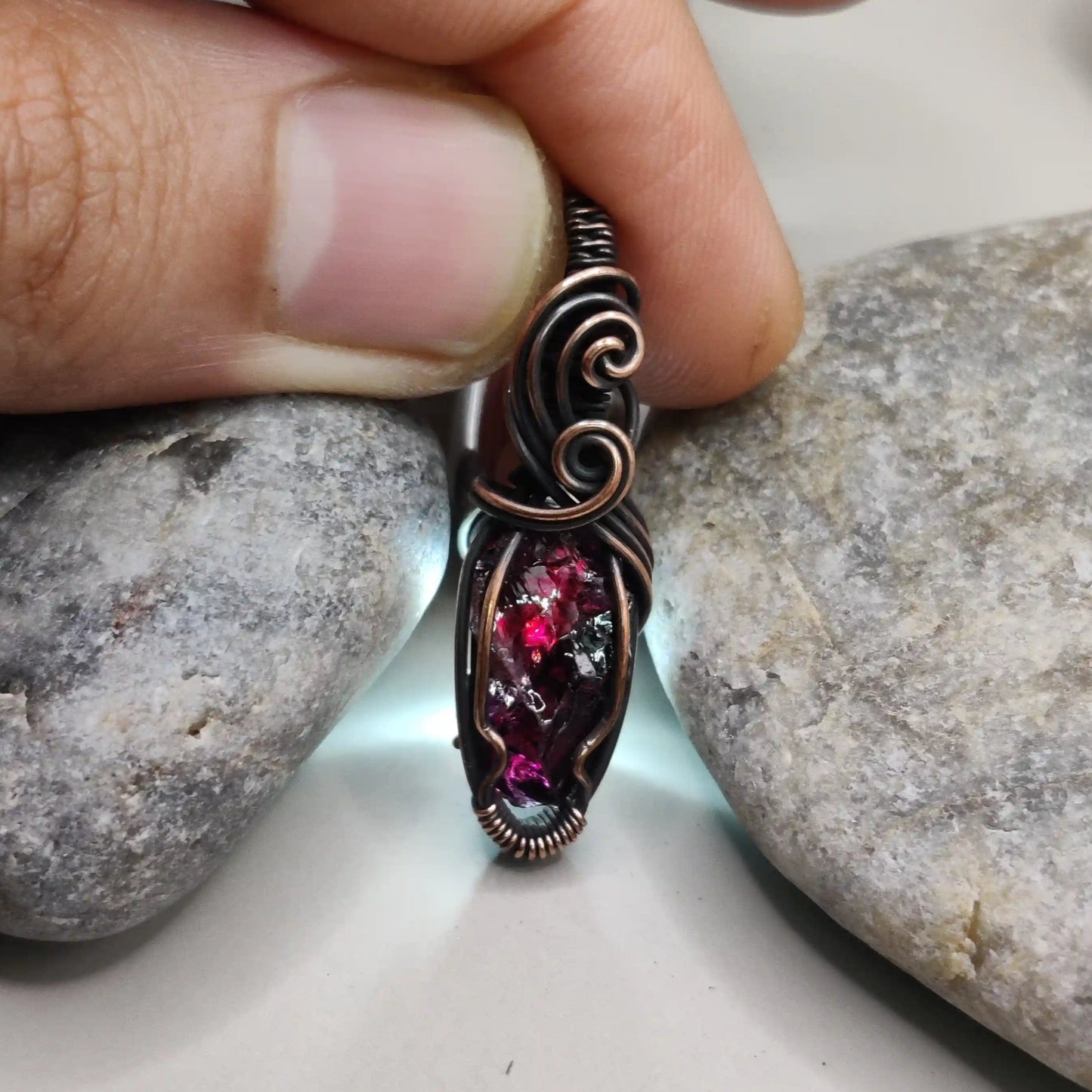 Niyati raw garnet pendant in antiqued copper 003 with light source in the background made by sanguine aura jewellery