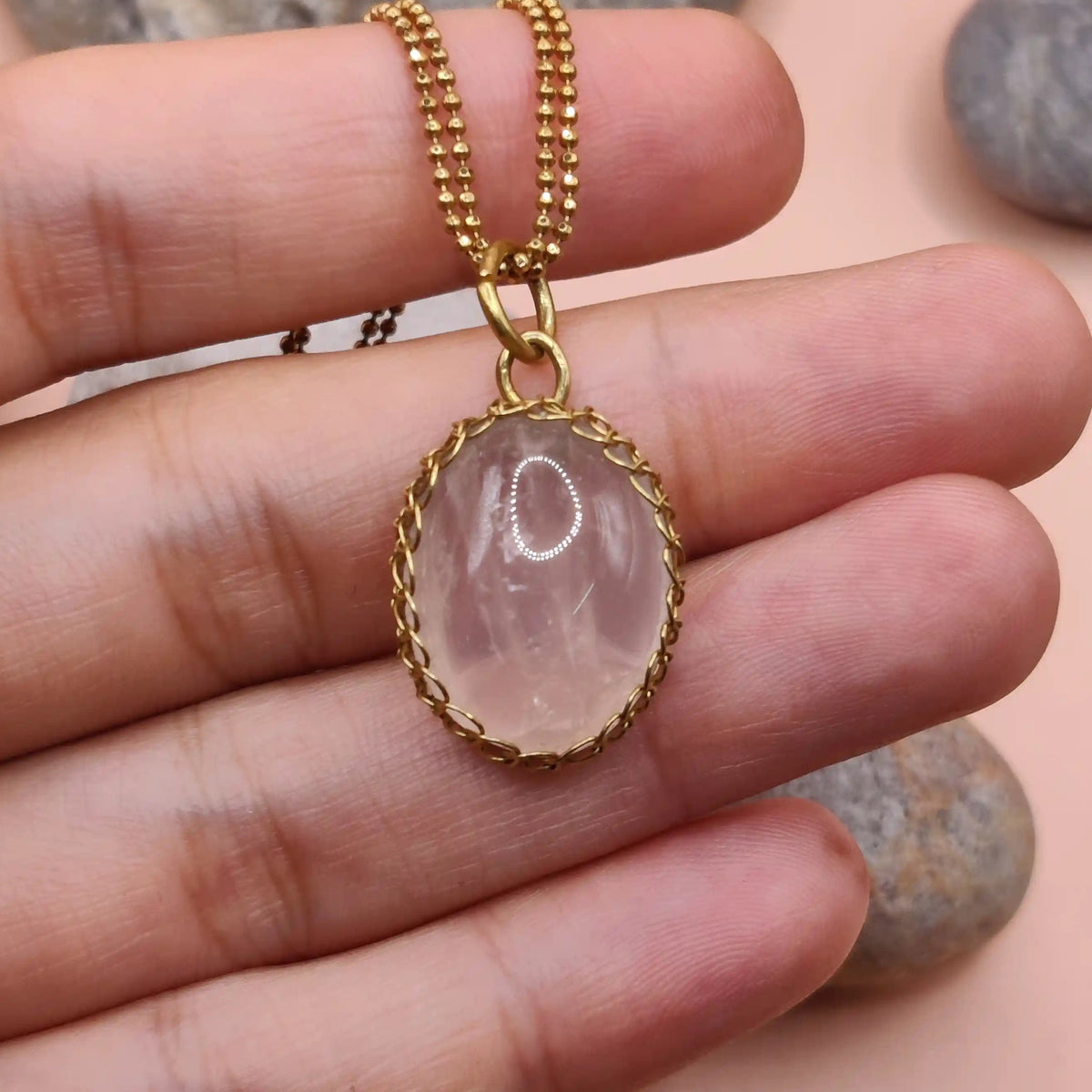 Meera rose quartz pendant in brass 005 held in hand, made in India with natural rose quartz and antibacterial brass.