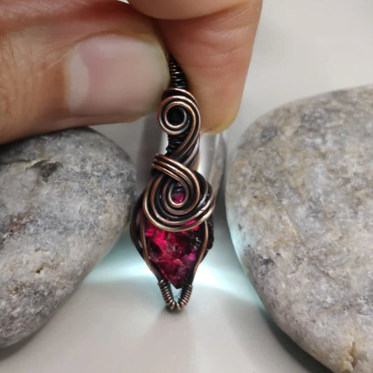 Niyati raw garnet pendant in antiqued copper 001 with light source in the background made by sanguine aura healing jewellery