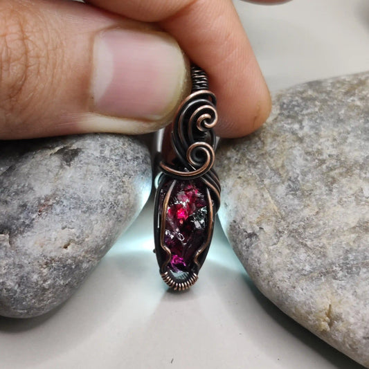 Niyati raw garnet pendant in antiqued copper 003 with light source in the background made by sanguine aura jewellery
